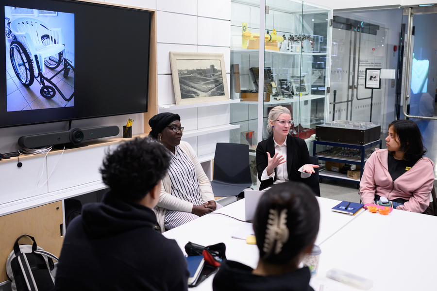 Amy Moran-Thomas sits at a table with students and visitors. 