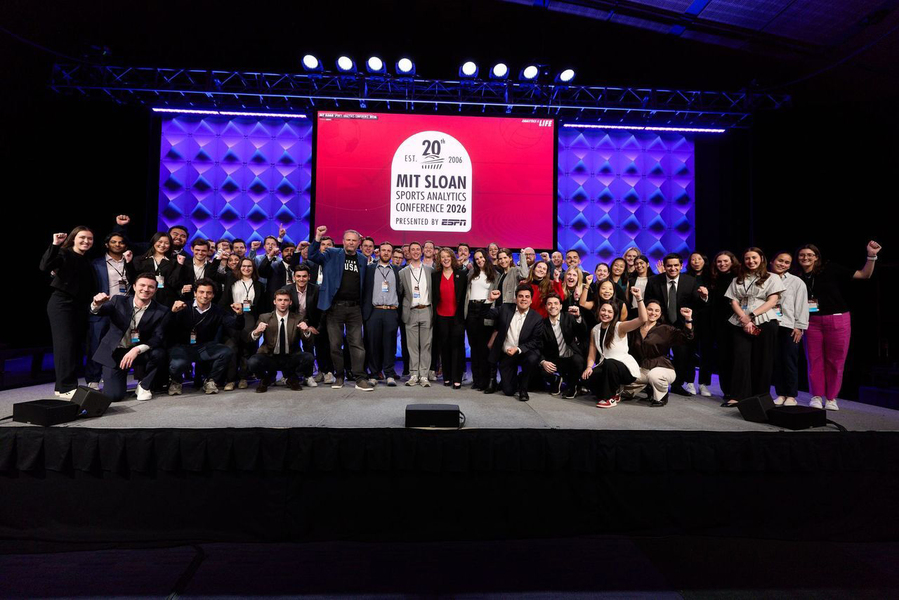 Around 100 people pose for portrait on stage with the text "MIT Sloan Sports Analytics Conference 2026" behind them.