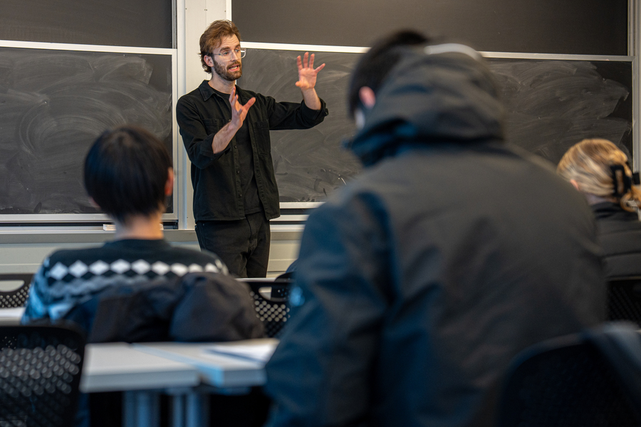 Michal Masny teaching in front of a blackboard in a classroom with students 