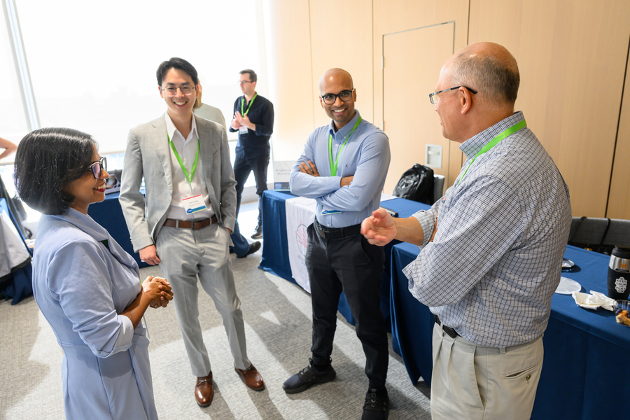 Four people stand in a circle talking indoors