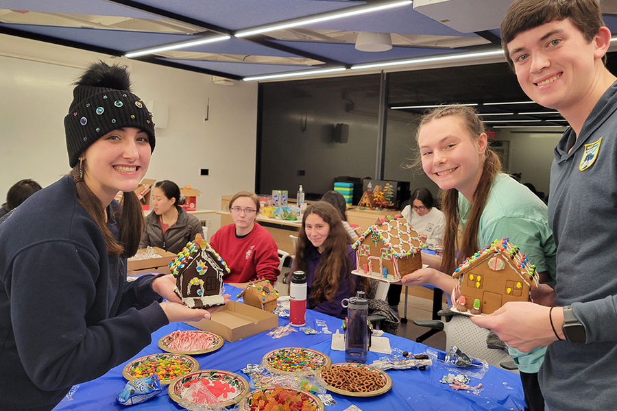 Half a dozen students show off the gingerbread houses they've just decorated