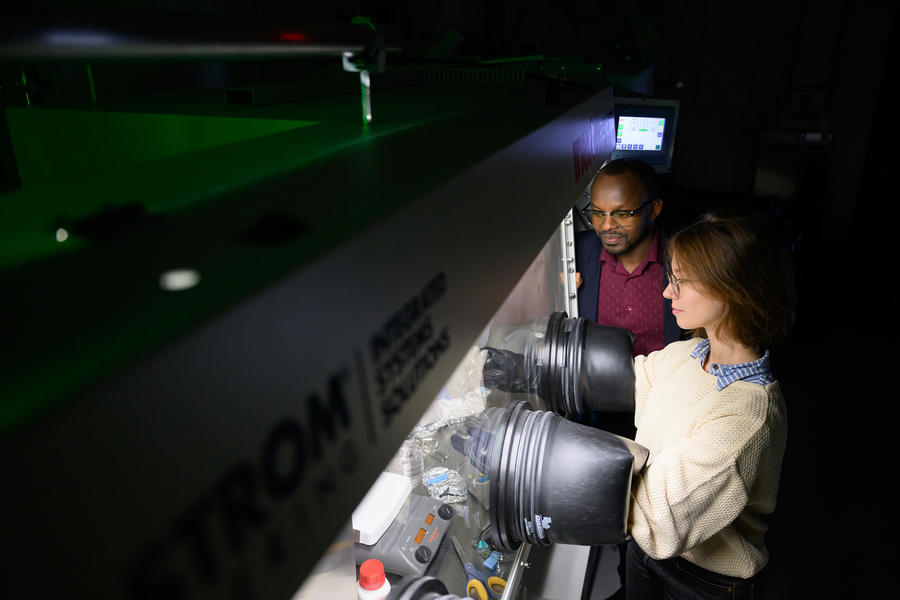 Camille Cunin places her hands into a glove box while Aristide Gumyusenge looks on.