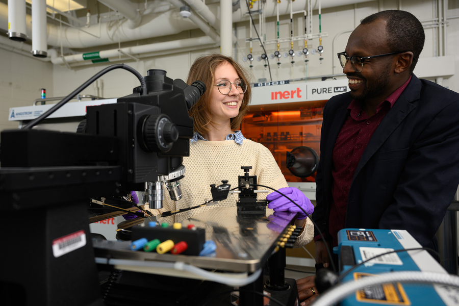 Standing in front of a microscope, Cunin and Gumyusenge look at each other and smile.