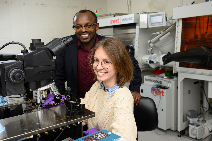 Cunin and Gumyusenge smile for a photograph in front of an optical microscope.