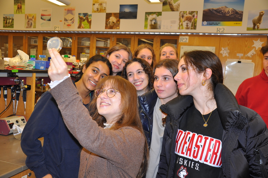 Valdes holds up a petri dish as 7 high school students look on