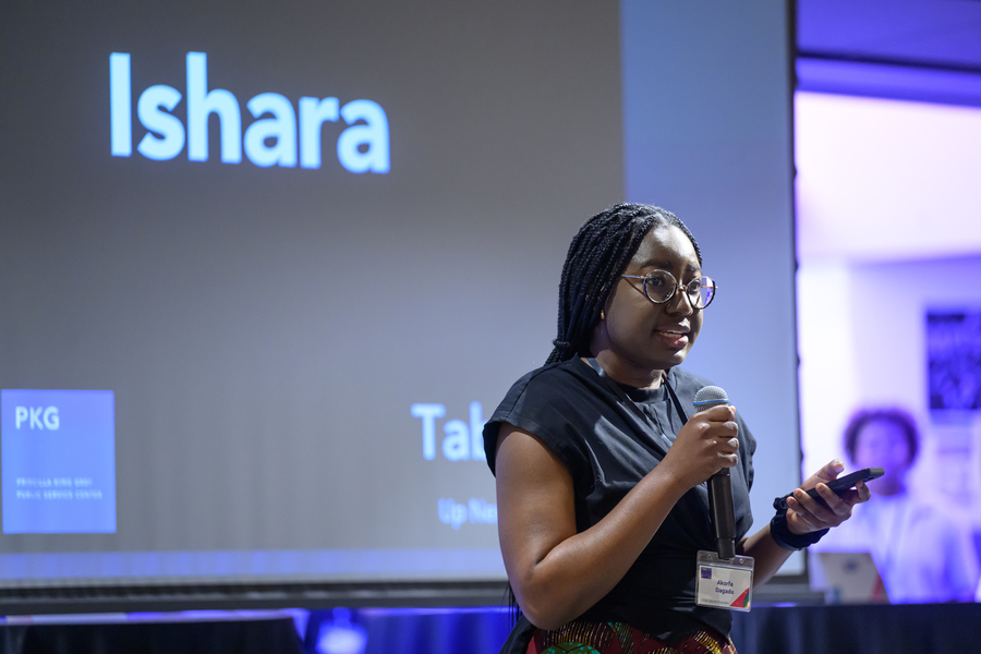 Akorfa Dagadu speaks at an indoor presentation. The word "Ishara" is projected on a screen behind her
