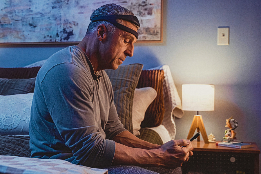 A man wears a unique headpiece, like a bandana, while getting ready for bed.