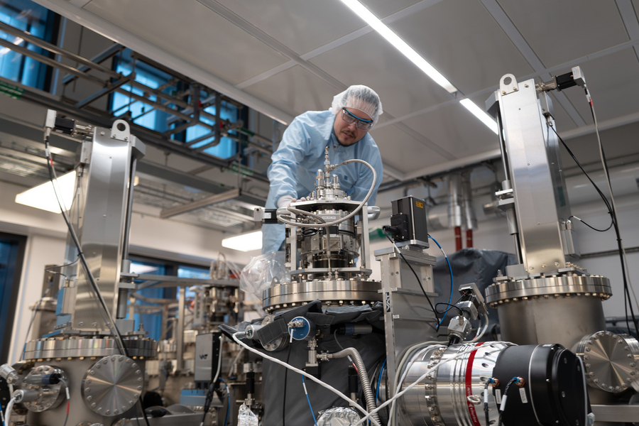 Patrick Strohbeen adjusts a valve while standing atop a large tank in a lab