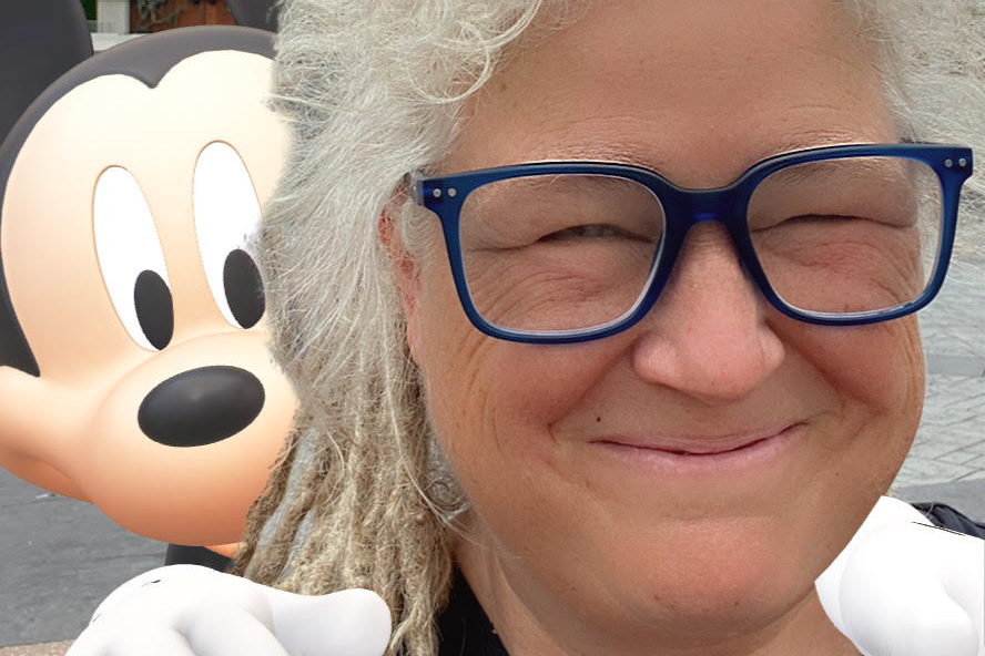 T.L. Taylor smiles in the foreground with an AR Mickey Mouse over her shoulder