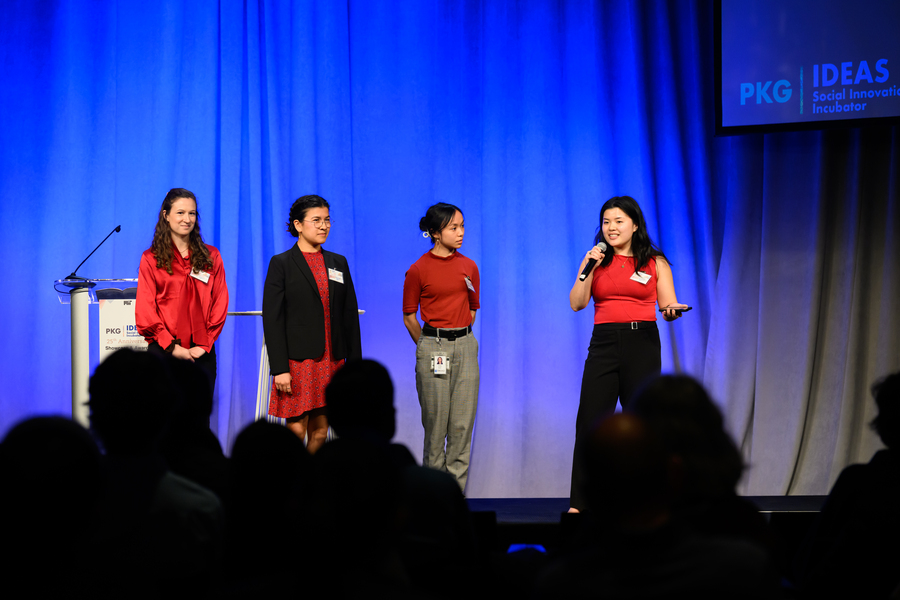 Four students speak on an indoor stage