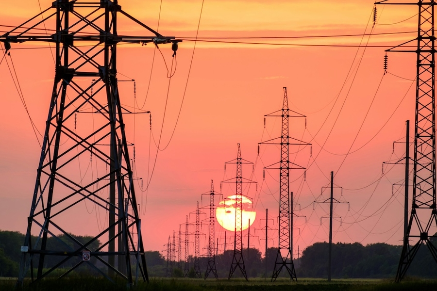 Photo shows silhouette of high-voltage power lines and towers during sunset