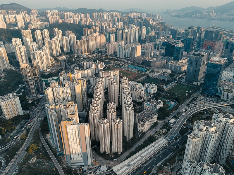 Aerial view of a dense part of Hong Kong with towering skyscrapers and intricate roadways.