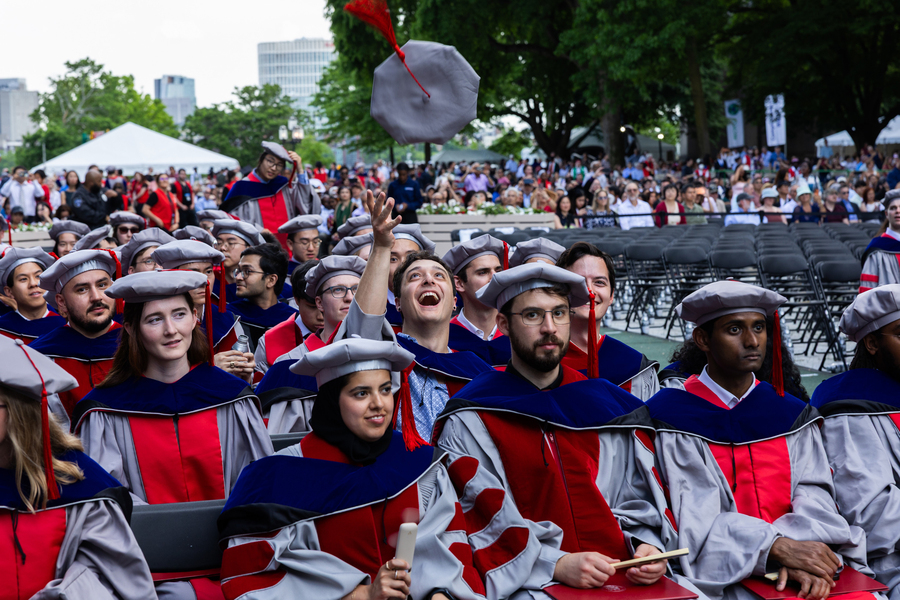 A PhD graduate throws his hat up while waiting for the event to start