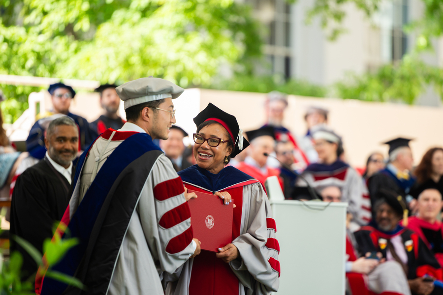 Paula Hammond hands a diploma to a grad.