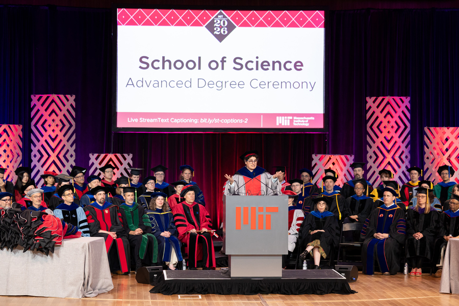 Nergis Mavalvala speaks at podium while surrounded by faculty members in regalia on stage.