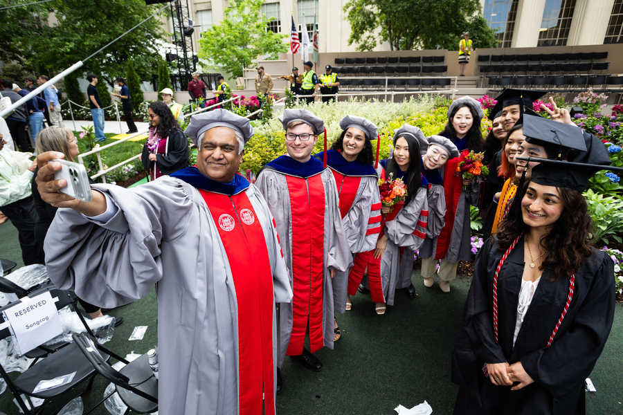 Anantha Chandrakasan takes a selfie photo with group of MIT graduates.