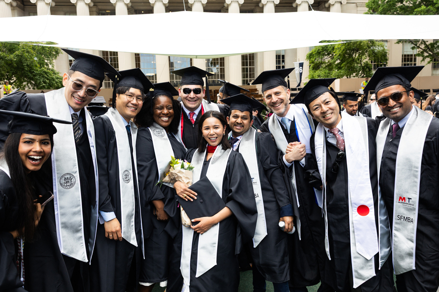 Ten graduates pose for portrait in their graduation regalia.