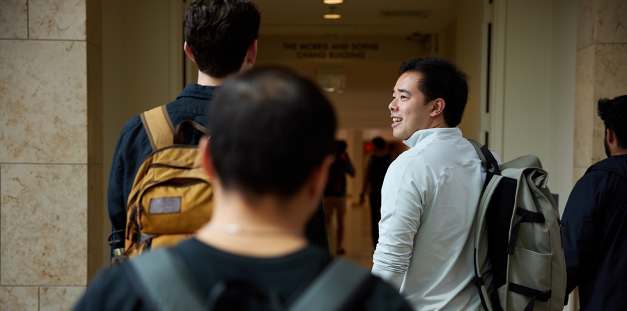 Students walking down a hallway, pictured from behind. 