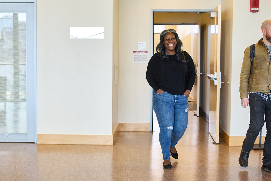 Alecia Asiamigbe walks out of a classroom into the main hallway, with another person exiting the frame of the image.