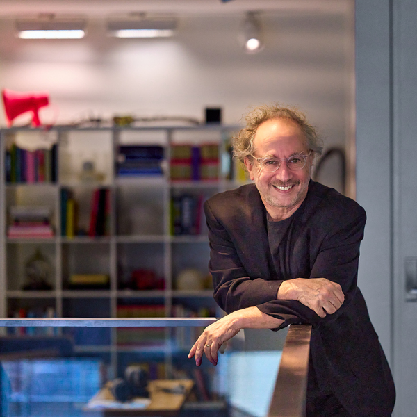 Tod Machover poses while leaning his forearms on a balcony railing