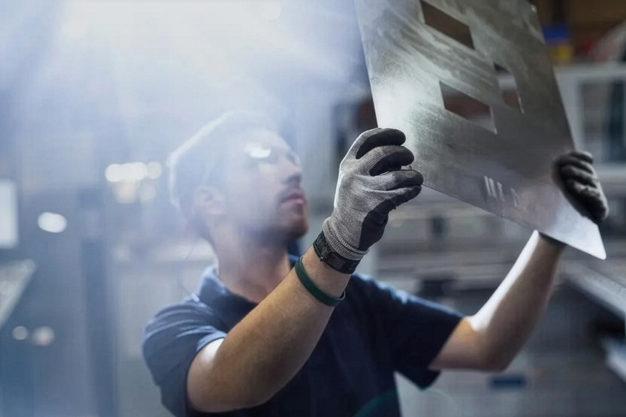 A worker looks at a sheet of steel.