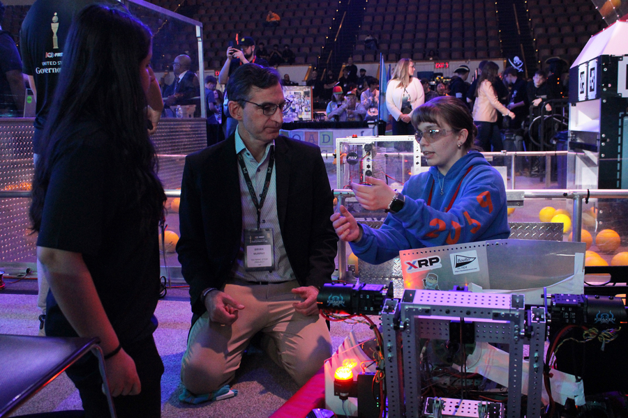 Bryan Murphy sits on the floor and chats with Angelina Kwiatkowski, with Timbot in the foreground.