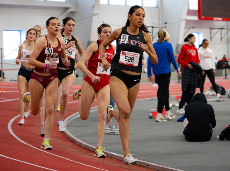Half-a-dozen women, led by Krystal Montgomery, run around a curve at an indoor track race
