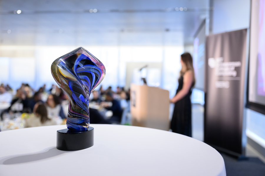 A glass trophy of swirled blue and yellow shapes rests on a table.