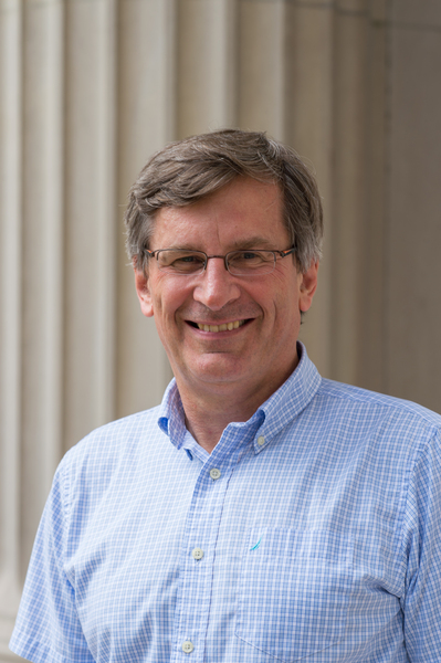 Bolek Wyslouch, wearing glasses and a light-blue button-down shirt, stands in front of the MIT pillars