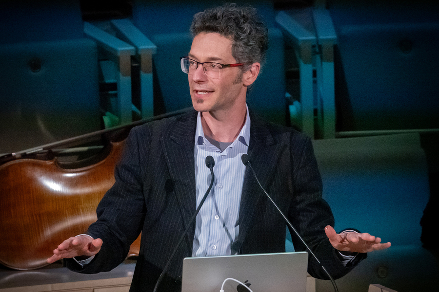 Eran Egozy speaks from an open laptop on a lectern