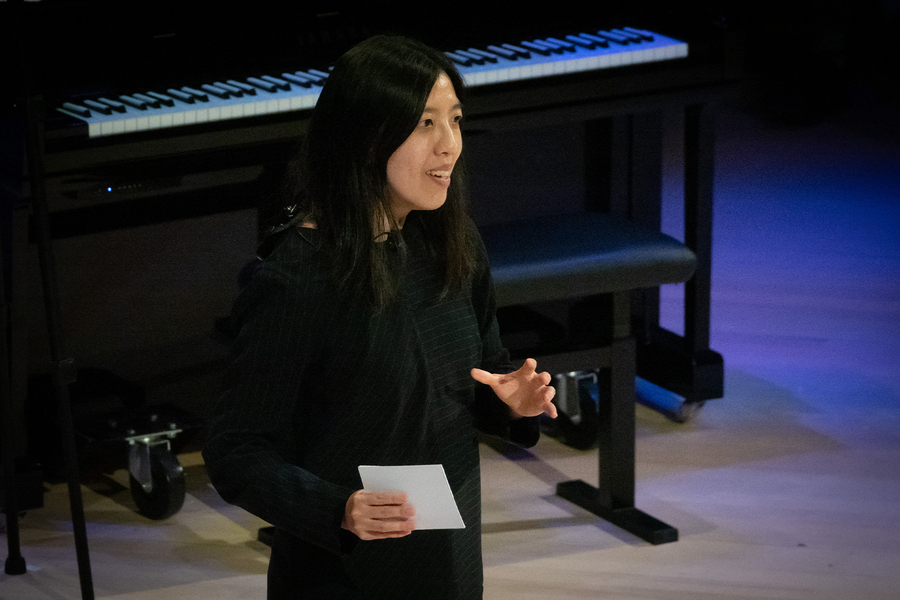 Anna Huang stands in front of a grand piano, poised to play.