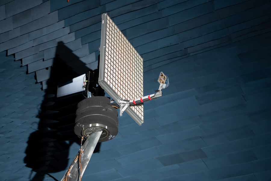 An antenna with 256 small, square elements in a 16x16 grid is held up in an anechoic chamber. 