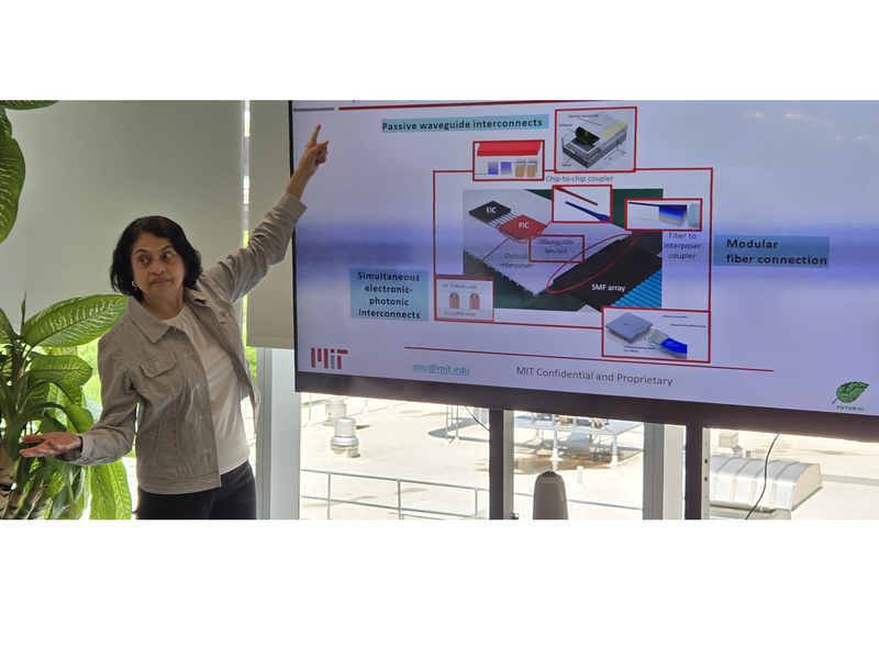 A woman gestures at a screen while presenting to an unseen audience.