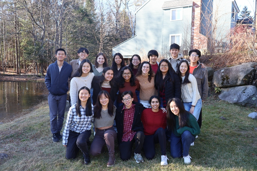 19 people pose outdoors in three rows on a spring day