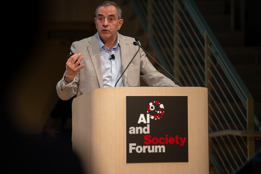 David Autor speaks from an indoor lectern that has a sign reading "AI and Society Forum."