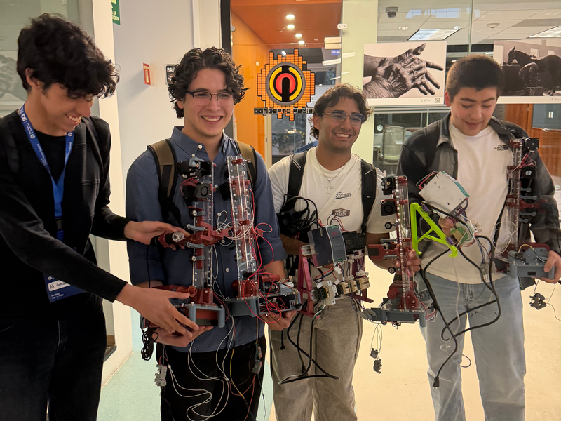 Four young men pose holding fiber extrusion devices.