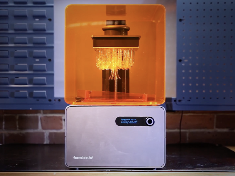 A Formlabs 3-D printer is a bright orange plastic cube atop a silver metal cube