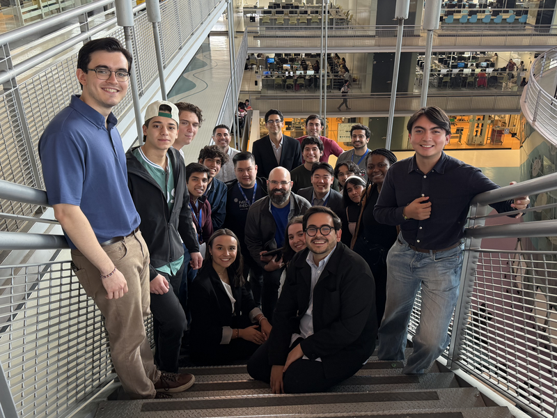20 people pose on a staircase, photographed from the top step