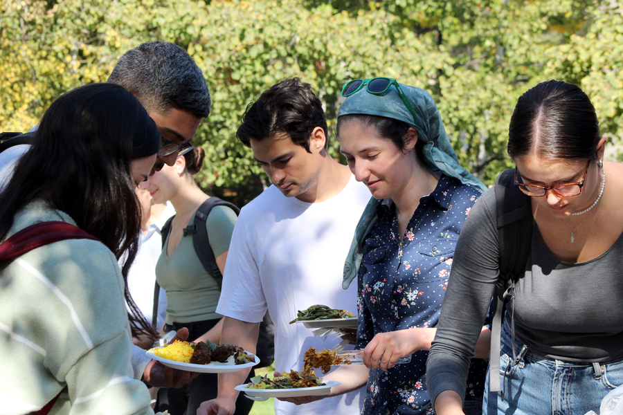 People get food outside at a buffet table
