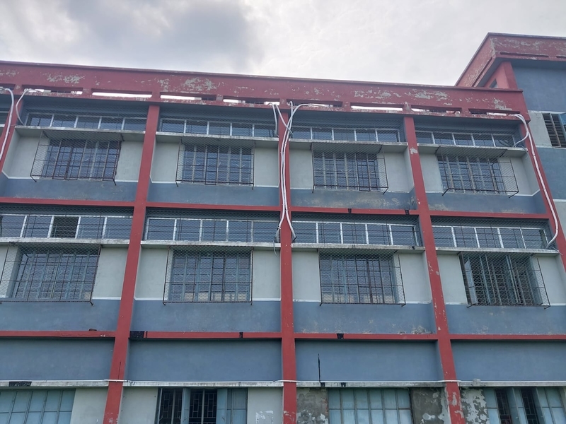 Gray-and-red concrete building with square windows encased in metal fencing