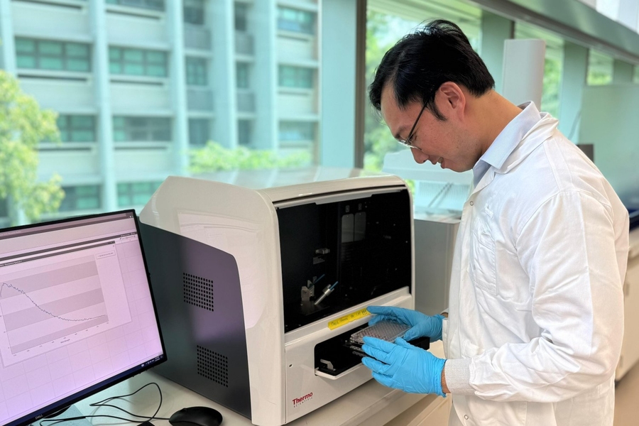 Mervin Ang places a sample inside a machine resembling a desktop microwave oven