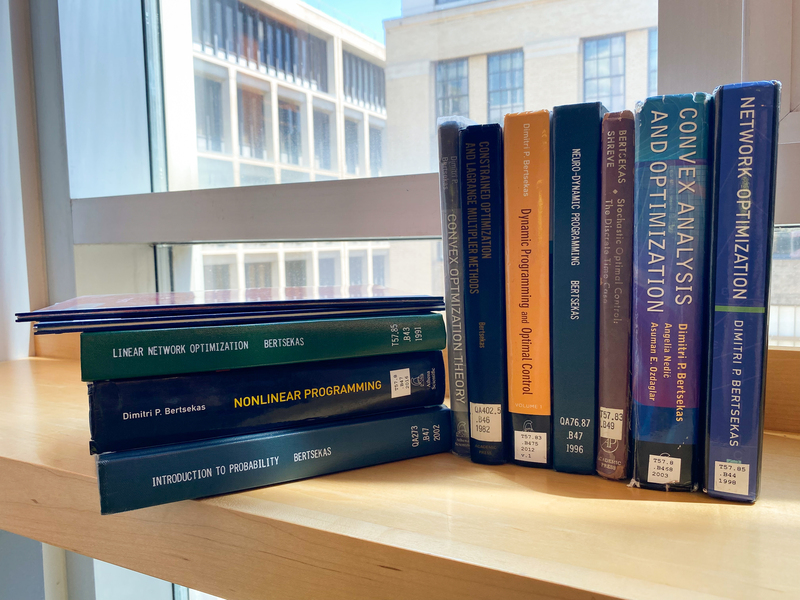 10 thick textbooks lean against each other on a windowsill inside MIT's Rotch Library