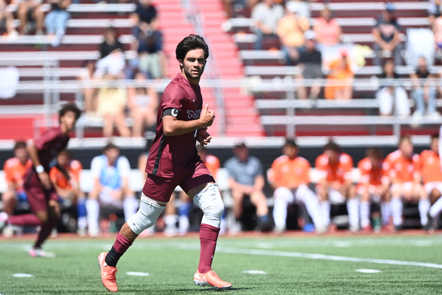 Dilin Meloni running on a soccer field with a crowd sitting in the stands in the background.