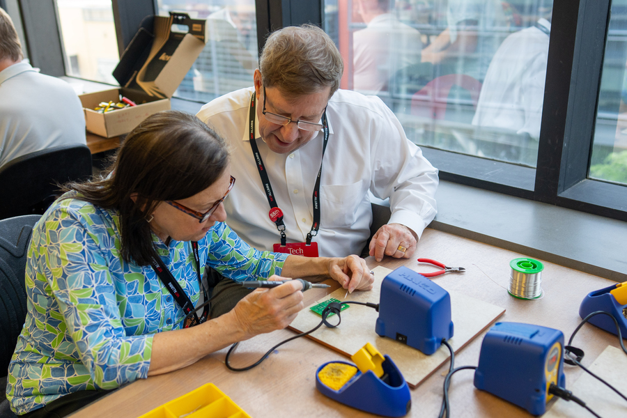 Alumni carefully mount components to PCB boards that will become makeshift electrocardiograms. 