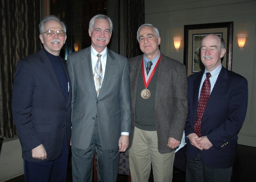 Tom Magnanti, Capers McDonald, Robert Cohen, and Robert Armstrong pose together in a dark dining room