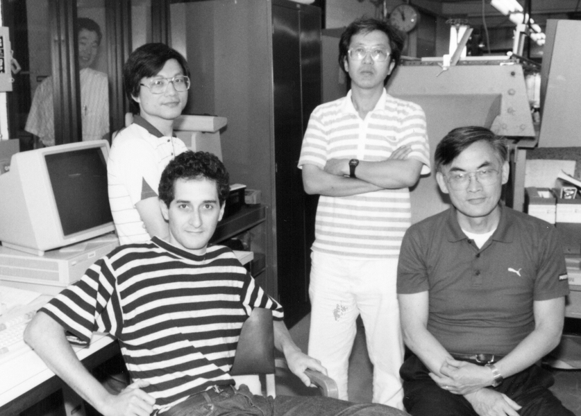 Grayscale photo of C.C. Mei in early middle age, sitting in a computer room with three of his students