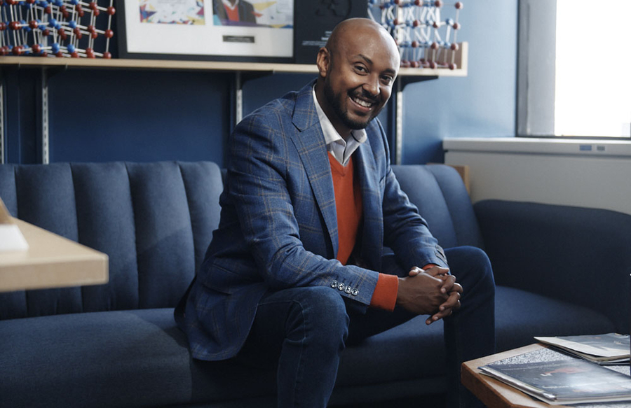 Iwnetim Abate poses seated on a blue couch in a small office