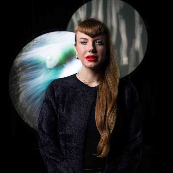 Amy Karle stands in front of a black background and two overlapping circular projections.