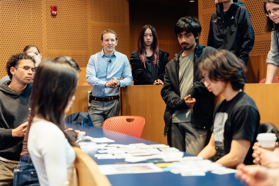 Instructor Carter Jernigan, wearing his in-class microphone, stands in the center of a group of students.