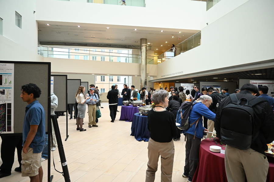 The atrium of MIT Building 46 is filled with people visiting research posters mounted on large easels